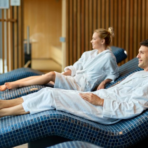 Relaxed couple wearing bathrobes while enjoying at health spa. Focus is on man.